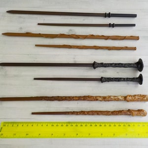 Puede incluir: Variedad de varitas de madera en tonos marrones, desde oscuros hasta claros. Algunas varitas tienen empu&ntilde;aduras texturizadas o elementos decorativos. Una regla amarilla en la parte inferior muestra medidas en cent&iacute;metros.