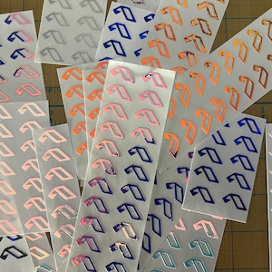 May include: Assortment of sheets of stickers with a repeating pattern of a stylized letter 'T' in various colors, including pink, blue, orange, and purple.