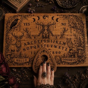 May include: A rectangular wooden spirit board featuring intricate laser-engraved illustrations of a central forest deity, a raven, a deer, an owl, and a fox. The board includes the alphabet, numbers 0-9, and the words YES, NO, HELLO, and GOODBYE.