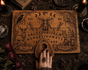 May include: A rectangular wooden spirit board featuring intricate laser-engraved illustrations of a central forest deity, a raven, a deer, an owl, and a fox. The board includes the alphabet, numbers 0-9, and the words YES, NO, HELLO, and GOODBYE.