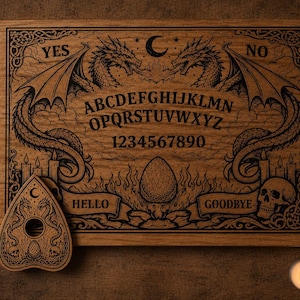 May include: A rectangular wooden spirit board featuring engraved black illustrations of two dragons, a crescent moon, skulls, and flames. The board displays the alphabet, numbers 0-9, and the words YES, NO, HELLO, and GOODBYE, accompanied by a matching planchette.