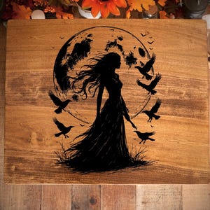 May include: A wooden decorative board with a dark silhouette of a woman in a long dress, standing before a full moon. Six crows fly around her. The board has a natural wood grain finish.