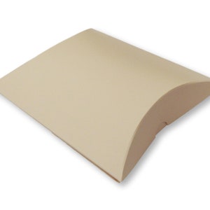 Könnte beinhalten: Eine hellbeige Kissenbox aus Pappe mit einer gewölbten Form. Die Box ist leer und bereit, mit einem Geschenk gefüllt zu werden.
