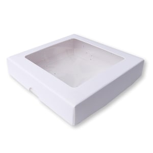 Puede incluir: Caja de cartón blanca con una ventana de plástico transparente en la parte superior. La caja está vacía.