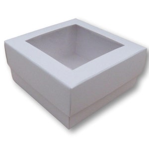 Puede incluir: Caja de cartón blanca con una ventana transparente en la parte superior. La caja está vacía.