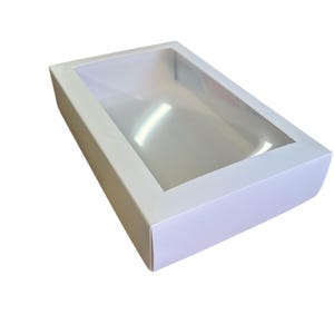 May include: White cardboard box with a clear plastic window on the top. The box is empty.