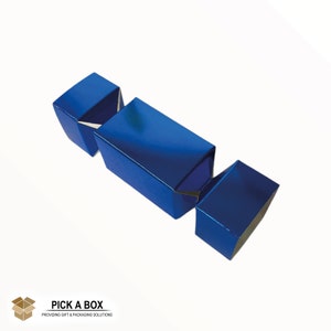 Puede incluir: Un cracker navideño azul metálico. El cracker está hecho de cartón y tiene un acabado brillante.