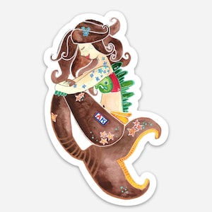 May include: A brown mermaid with a green and red tail, blue flowers on her arm, and a red and white top. She is sitting with her head down and has brown hair with a blue flower in it. The mermaid has a patch on her tail that says "AK".