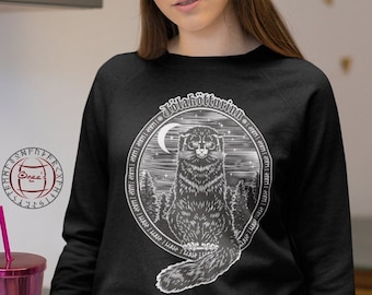 May include: Black sweatshirt with a white graphic of a cat sitting in a forest with a crescent moon and stars. The graphic is surrounded by a circle with the text "Jivabhottuvin" in a stylized font.