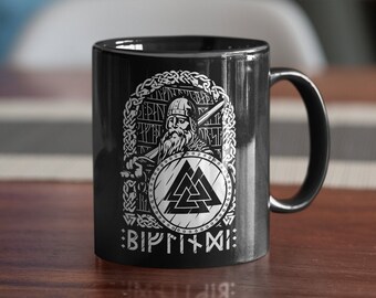 May include: Black ceramic mug with a white design of a Viking warrior holding a shield with a Valknut symbol and the text "Bíþr til Vígs".
