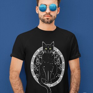 May include: Black t-shirt with a white graphic of a black cat with green eyes sitting in a circle of stars and the text "SAMHAIN" repeated around the circle.