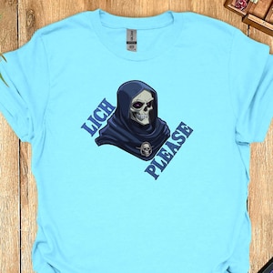 May include: A light blue t-shirt with a graphic of a hooded skeleton with the text "Lich Please" on a diagonal.