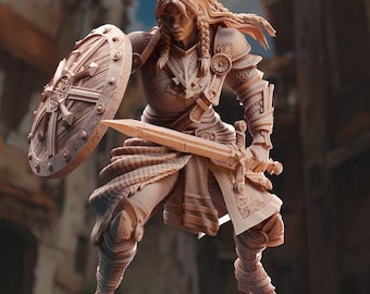 May include: A detailed figurine of a female warrior in a pose of defense, holding a sword and a round shield with a sunburst design. The figurine is made of a light brown material and is standing on a rocky base.