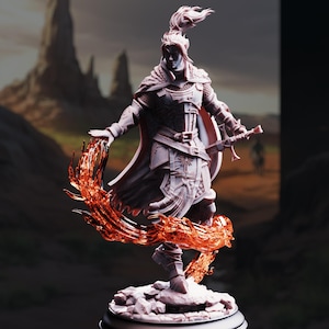 May include: A detailed figurine of a warrior in armor, holding a sword and shield, with a flowing cape and feathered helmet. The figure is surrounded by a fiery, orange energy effect, standing on a rocky base. The background shows a mountainous landscape.