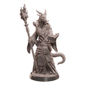 May include: A detailed miniature figurine of a dragon-like creature wearing a robe and holding a staff with a flame at the top. The creature is holding a book in its left hand. The figurine is painted in a light brown color.