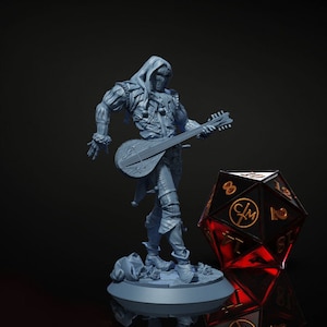 May include: A gray 3D printed miniature of a jester playing a lute. The jester is wearing a hooded costume with bells and is standing on a round base. A red and black D8 dice is in the background.