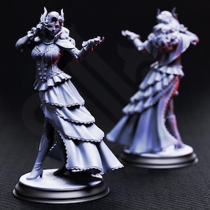 May include: Two detailed figurines of a woman in a long, layered dress and mask. The figures are on round bases, with one in full view and the other in the background. The dress has a ruffled design, and the woman is posed with one arm extended.