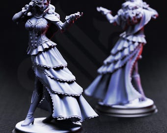Pode incluir: Duas figuras detalhadas de uma mulher em um vestido longo e em camadas e uma máscara. As figuras estão em bases redondas, uma em plena vista e a outra ao fundo. O vestido tem um design com babados, e a mulher posa com um braço estendido.