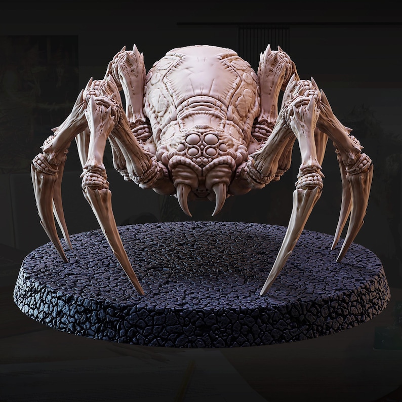 May include: A detailed, beige-colored spider figurine with multiple eyes and sharp fangs. The spider has long, pointed legs and is posed on a textured, dark gray circular base. The figurine is likely for tabletop gaming or display.