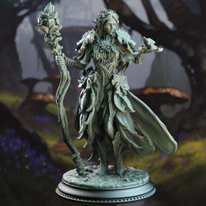 May include: A detailed figurine of an elven woman, sculpted in a muted green hue. She wears a dress and cape adorned with leaf-like details, and holds a staff topped with a flower. The figure stands on a circular base, with a blurred forest background.
