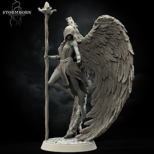 May include: A gray, detailed, sculpted figurine of a winged woman holding a staff. The woman is wearing a hooded robe and has a staff with a bird-like head on top. The figurine is standing on a round base.
