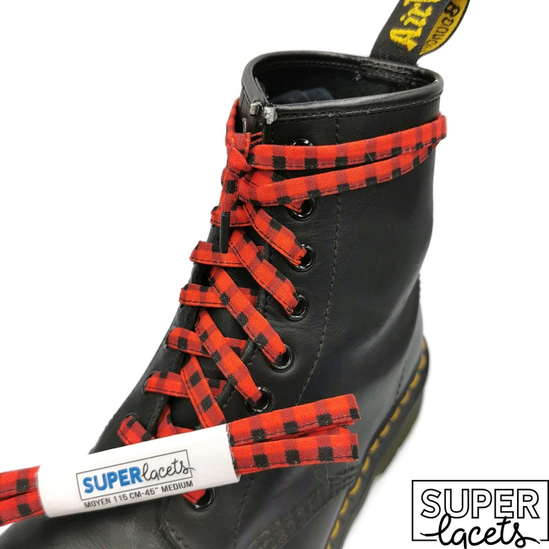 Pu&ograve; includere: Lacci per scarpe a scacchi rossi e neri con il testo "SUPERlaces" e "MOYEN 115 CM-45" su un'etichetta bianca. I lacci sono legati a un paio di stivali in pelle nera.