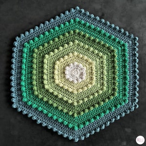 hexagon shaped crocheted bath mat in green tones, on a black background