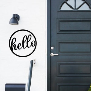 May include: A black metal sign with the word "hello" in a cursive font, mounted on a white wall next to a black door with a glass window.