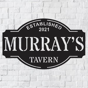 May include: Black metal sign with white lettering that reads "Established 2021 Murray's Tavern".