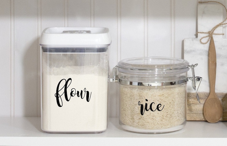 May include: Two clear plastic containers with labels on the front. The container on the left is labeled "flour" and the container on the right is labeled "rice".