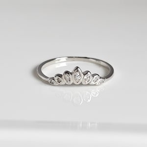 May include: A silver ring with a row of small, clear stones set in a crown shape.