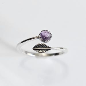 May include: A silver ring with a purple gemstone and a leaf design.