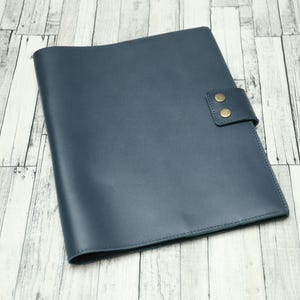 May include: A dark blue leather folder with two brass snaps on the front flap.