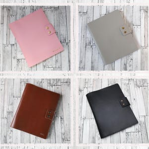 May include: Four leather folders in different colors: pink, gray, brown, and black. Each folder has a flap with two brass snaps.