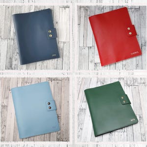 May include: Four leather-bound notebooks in different colors: navy blue, red, light blue, and green. Each notebook has a flap with two brass buttons and personalized initials.