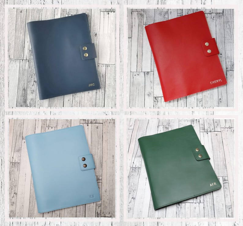 May include: Four leather-bound notebooks in different colors: navy blue, red, light blue, and green. Each notebook has a flap with two brass buttons and personalized initials.