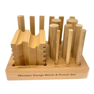 May include: Wooden swage block and punch set with a variety of sizes. The set includes a wooden block with different shaped grooves and a set of round wooden punches in sizes 6mm, 8mm, and 11mm.