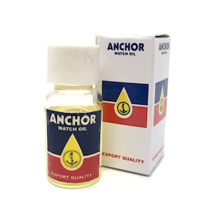 May include: A small glass bottle of Anchor Watch Oil with a yellow label and a red, white and blue anchor logo. The bottle is next to a white box with the same logo and the text "Anchor Watch Oil" and "Export Quality".