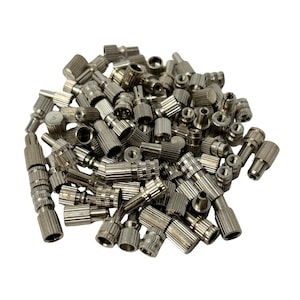 May include: A collection of small, silver-coloured metal knobs. The knobs have a variety of shapes and sizes, with ridged and smooth surfaces. Some have threaded ends. The pile of knobs is set against a white background.