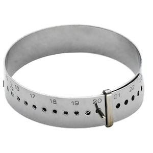 May include: A silver metal ring sizer with a sliding clasp and numbered markings from 15 to 22.