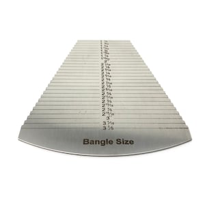May include: A silver metal bangle size gauge with a graduated scale of measurements from 1 1/8 inches to 3 1/8 inches. The gauge is labelled "Bangle Size".