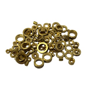 May include: A pile of small, brass-coloured metal components, including rings, cylinders, and other shapes. The components vary in size and have a shiny, metallic finish. These parts are likely used in manufacturing or mechanical applications.