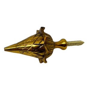 May include: A gold-coloured furniture knob with a conical shape and a textured surface. The knob has a screw for attachment and a rounded base. The design features a geometric pattern.