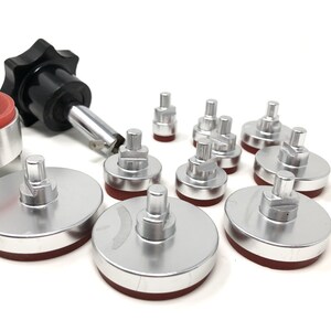 May include: A set of 11 silver-colored watch case back press tools with red rubber bases. The tools are used to press watch case backs on and off.