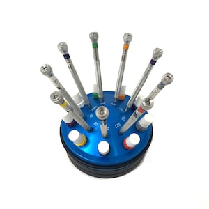 May include: A blue watch repair tool set with eight screwdrivers in a rotating stand. The screwdrivers have different coloured handles and are labelled with numbers.