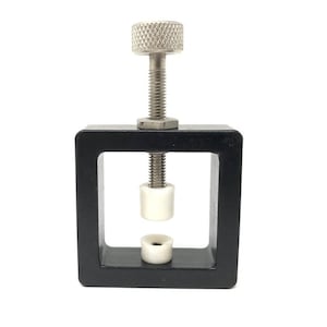 May include: A black metal clamp with a silver screw and knob. The clamp has two white plastic inserts.
