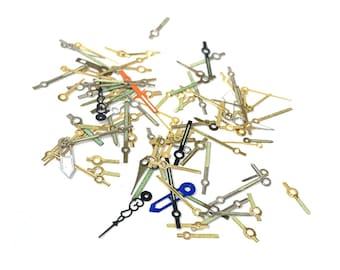 May include: A collection of assorted watch hands in various colors, including gold, silver, black, blue, green, and orange. The hands are made of metal and have different lengths and styles.