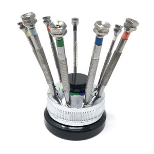 May include: A set of eight watchmaker screwdrivers with coloured handles, organised in a rotating stand. The screwdrivers are made of metal and have different sized tips.