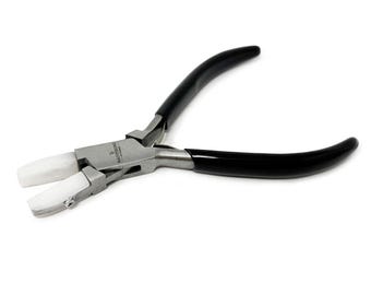 May include: Jewellery pliers with black handles and white, plastic-coated jaws. The pliers are made of silver-coloured metal and are designed for precision work. The handles are curved for a comfortable grip.