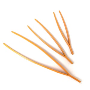 May include: Three orange plastic tweezers of varying lengths. The tweezers are arranged in a fan shape.